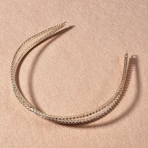 Détail d'un serre-tête doré à double rangée de strass avec un design croisé élégant