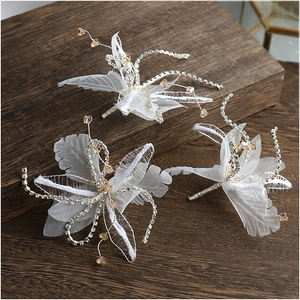 Three-piece bridal hair pins with white lace flowers and rhinestone tassels on wood