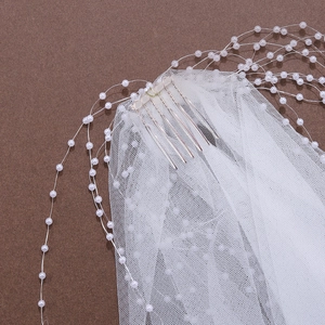 Detail of bridal veil with white pearls and metal hair comb on textured background