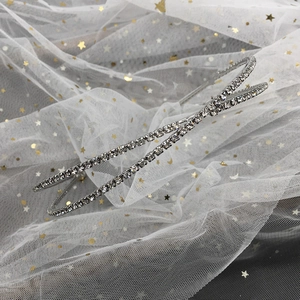 Détail du serre-tête de mariage croisé en métal argenté et strass blancs brillants