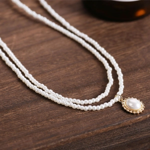 Close-up of double-layer pearl necklace with oval pendant on a vintage gold base