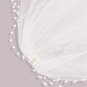 Elegant bridal veil with white pearls and metal hair comb on soft white tulle
