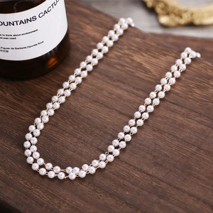 Double-layered pearl necklace with oval pendant on vintage wooden background for brides