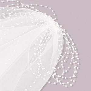 Detail shot of delicate bridal veil with white pearl beads and soft sheer tulle fabric