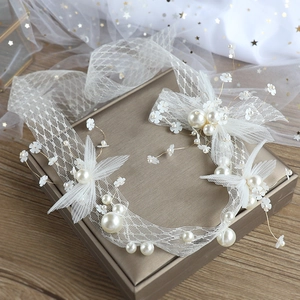 Elegant bridal hairband with white lace flowers and pearls on a golden display case