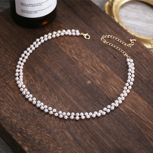Detail of double-layer pearl necklace with gold lobster clasp on vintage wood background