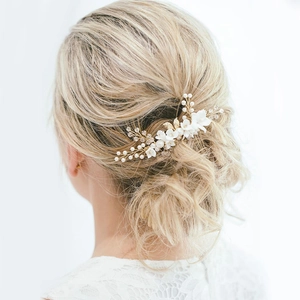 Elegant white floral bridal headpiece with pearls and gold leaf accents on a wedding updo