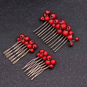 Detail of three bridal hair combs with matte red pearls and gold wire craft