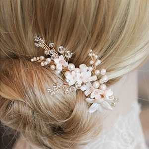 Romantic bridal headpiece with white flowers, pearls, and gold wire on a model