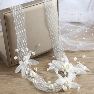 Elegant bridal headpiece with white lace flowers and pearls on a vintage mesh headband