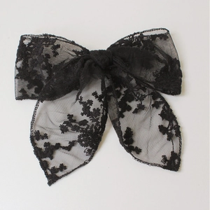 Detalle de un lazo para el pelo en encaje negro con bordado floral delicado