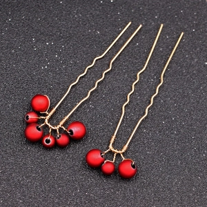 Detail of two handmade gold U-shaped bridal hair pins with frosted red beads