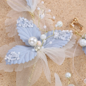 Macro detail of handmade bridal headpiece with blue fabric leaves and pearls