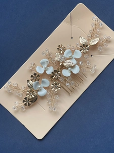Detail of bridal hair comb with gold leaves, white petals, pearls, and crystals