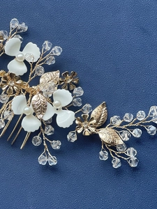 Macro detail of bridal hair comb with gold leaves, white flowers and crystals