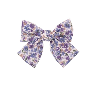 Detalle de pinza para el pelo con lazo de encaje floral y bordado en violeta y rosa
