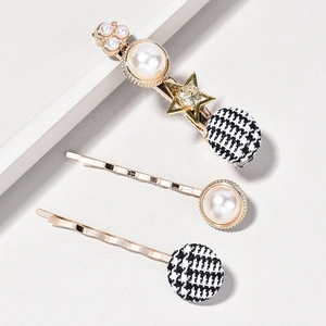 Detail view of 3-piece vintage pearl hair clips with houndstooth and golden star accents