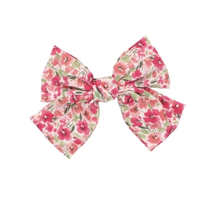 Detalle de pinza para el pelo beige con bordado floral rosa y rojo en forma de lazo