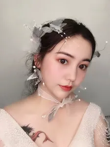 Close-up of white tulle bridal hairpiece with feathers and matching pearl earrings