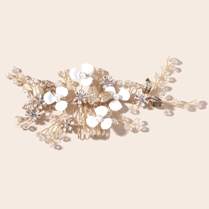 Detail of bridal hair comb with gold leaves, white flowers and crystals for weddings