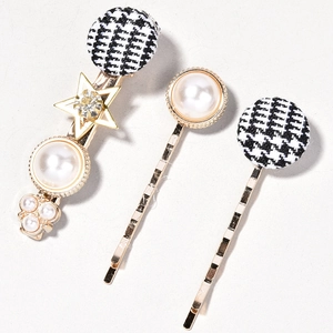 Detail of a 3-piece hair clip set featuring pearls, houndstooth patterns and golden stars