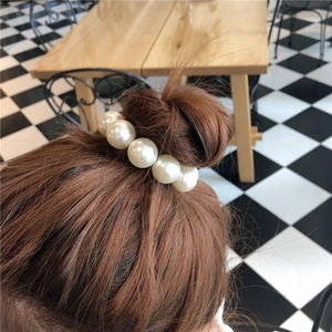 Élastique à cheveux perlé minimaliste sur un chignon avec de grandes perles blanches