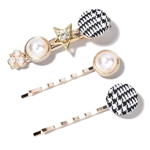 Detail of vintage pearl hair clips set with golden star and houndstooth pattern fabric