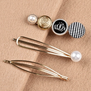 Close-up of vintage hair pins set with pearls, crown logo, and houndstooth fabric detail