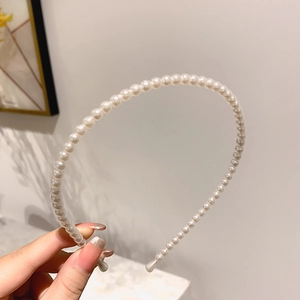 Elegant white pearl beaded headband held in hand, minimalist fashion hair accessory