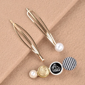 Detail view of pearl hairpins with lion crest, crown emblem, and houndstooth pattern