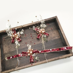 Détail d'épingles à cheveux et tour de cou rouges avec feuilles dorées et perles