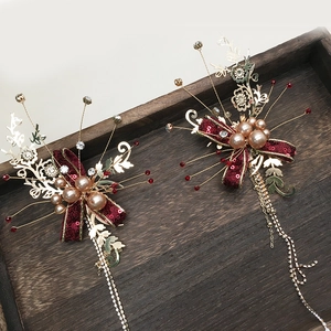 Détail de pinces à cheveux de mariée avec nœuds rouges et pompons dorés avec perles