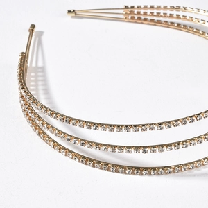 Détail d'un serre-tête doré multicouche orné de trois rangées de strass étincelants