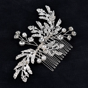 Macro shot of silver bridal hair comb with rhinestone leaves and white pearls decoration