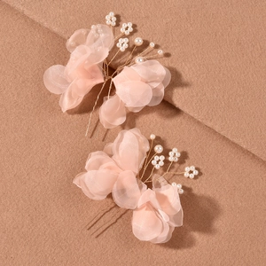 Detail of pink organza flower hair pins with white pearls on a soft textured background