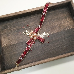 Vue détaillée du ruban de cheveux à paillettes rouges avec feuilles d'or et perles