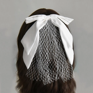Détail d'un nœud en satin blanc avec un voile en résille délicat pour coiffure mariée