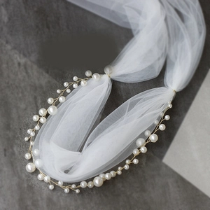 Close-up of white pearls woven on gold wire with delicate bridal organza mesh