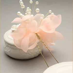 Close-up of a pink tulle flower bridal hair pin with delicate white pearls and golden U-shaped clip