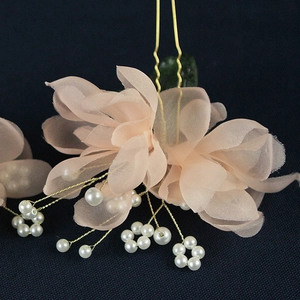 Detailed macro view of soft pink gauze flowers and white pearls on golden bridal hair pin