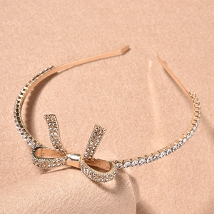 Dettaglio ravvicinato del cerchietto in oro rosa con fiocco e strass luccicanti