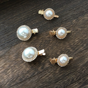 Macro view of 5 champagne gold pearl hair clips with rhinestones on dark wood