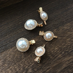 Detailed close-up of five champagne gold pearl and rhinestone bridal hair clips