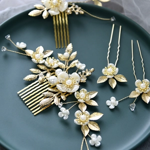 Détail d'un peigne à cheveux de mariée avec feuilles dorées, fleurs et perles blanches
