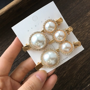 Detail of champagne gold hair clips with large faux pearls and sparkling rhinestone edges