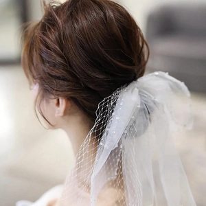Close-up of white bridal bow veil featuring delicate mesh fabric and shimmering sequins