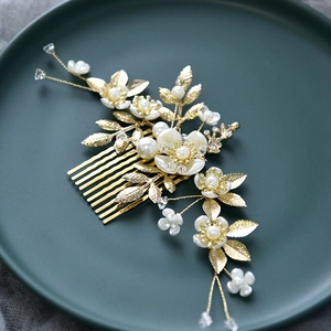 Détail du peigne de mariée avec feuilles dorées, fleurs en résine et perles