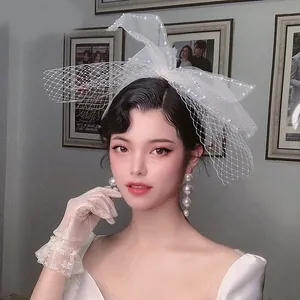 Detail of vintage bridal bow veil with lace gloves and elegant long pearl earrings