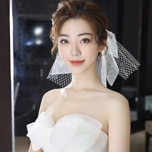 Close-up of white bridal bow veil with pearls and soft tulle mesh for wedding hair
