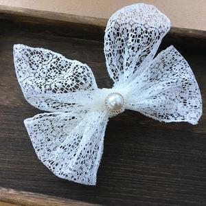Eleganter weißer Spitzen-Haarclip mit Perle auf einem vintage Holztablett
